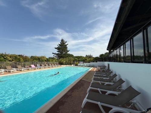 une piscine avec des chaises longues et une personne qui nage dedans dans l'établissement Le domaine de la billardière, à Moutiers-les-Mauxfaits