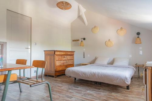 a bedroom with a bed and a table and chairs at Gîte Lunaben-Maison en pierres avec piscine in Forges