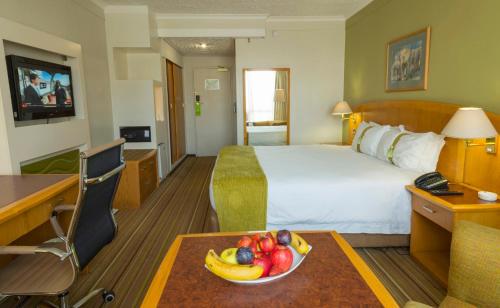 a hotel room with a bed and a bowl of fruit on a table at Holiday Inn - Harare by IHG in Harare