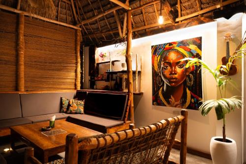 a room with a table and a painting of a woman at Tribe Bungalows, Bwejuu, Zanzibar in Bwejuu