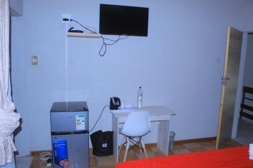 a room with a desk and a television on the wall at Arrival Center BnB in Maseru