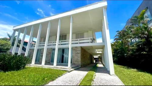 イタジャイにあるCasa Niemeyerの芝生のある白い建物の外観