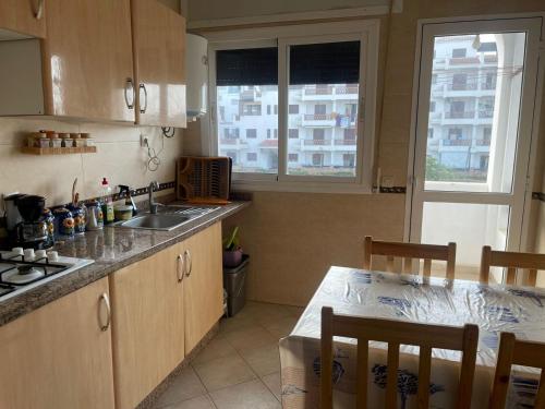 a kitchen with a sink and a table with chairs at Appartement à oued laou mekkad in Oued Laou