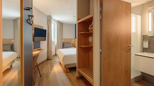 a small room with a bed and a desk and a bedroom at Kyriad Anglet - Biarritz in Anglet