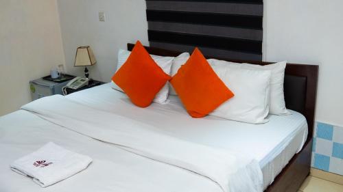 a bed with orange and white pillows on it at Mende Hotel in Lagos