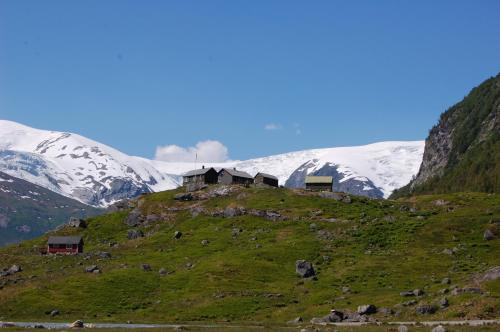 a group of houses on a hill with snow covered mountains at Eikum Hotel in Hafslo