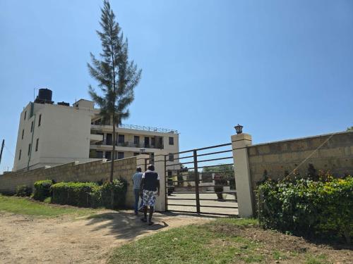 two people walking up a fence in front of a building at Walabi Mara Hotel in Narok