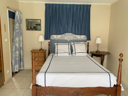 une chambre avec un grand lit avec des rideaux bleus dans l'établissement Coastal bliss, à Grand-Village-Plage