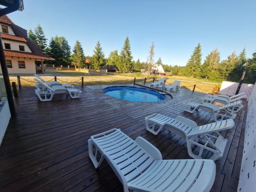 una terrazza in legno con sedie e una piscina di Vila Tri Srca a Beserovina