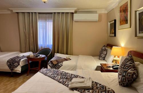 a hotel room with three beds and a table at Mass Plaza Hotel in Aqaba