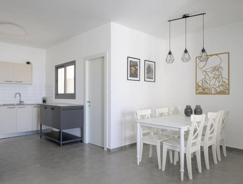 Una cocina y un comedor con una mesa y sillas blancas. en The most special 3-BDR on Achziv, en Nahariyya