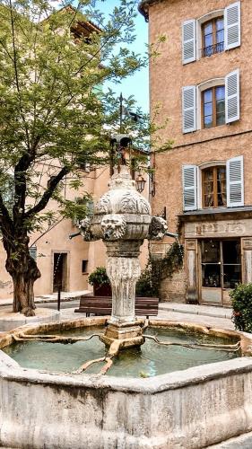 a fountain in front of a building with a building at Loft avec balcon in Cotignac