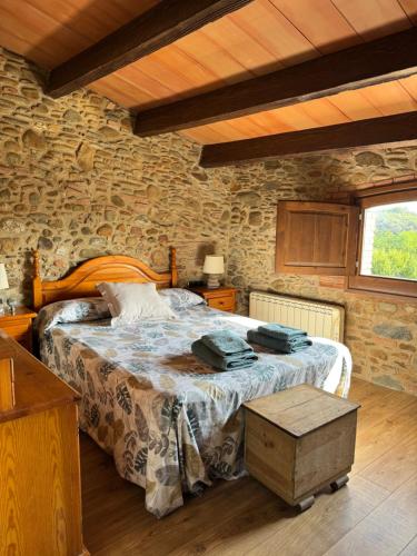 a bedroom with a bed and a stone wall at Ca l'Esclatat in Santa María de Palautordera