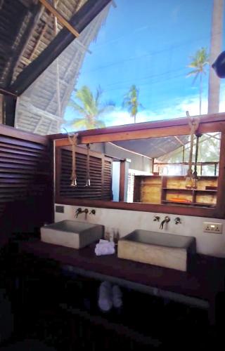 two sinks in a bathroom with palm trees in the background at Banja Amani Lodge Mafía Island in Mafia Island