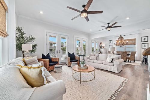 Il comprend un salon doté d'un mobilier blanc et d'un ventilateur de plafond. dans l'établissement Mer Soleil, à Orange Beach
