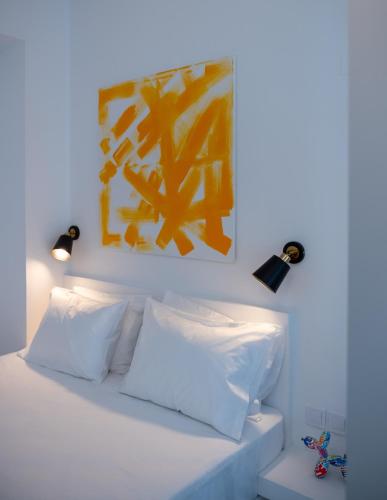 a bed with white pillows and a painting above it at Petite maison in Itea