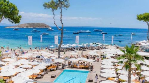 a beach with white umbrellas and a swimming pool at Villa Dinastía Resort Lujo in Llucmajor