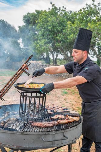 a man is cooking food on a grill at Villa Dinastía Resort Lujo in Llucmajor