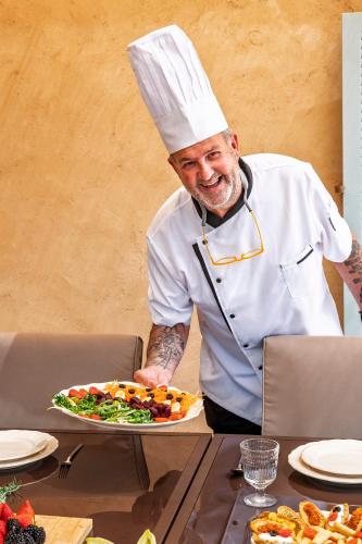 a chef holding a plate of food on a table at Villa Dinastía Resort Lujo in Llucmajor