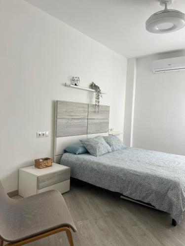 a white bedroom with a bed and a chair at Apartamento Llimera Altea in Altea