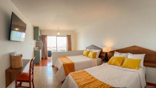 Una habitación de hotel con dos camas y un televisor. en MONACO Chicama Beach, en Puerto Chicama