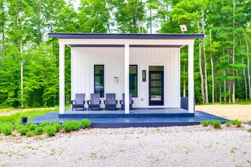 una pequeña casa blanca con sillas en un patio en Modern Bellaire Cabin Less Than 5 Mi to Lake and Slopes!, en Bellaire