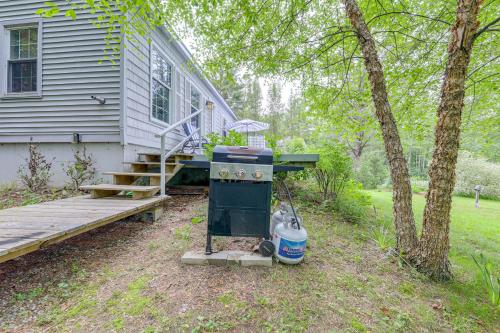 a house with a stove next to a wooden deck at Beautiful Mousam River Retreat Hot Tub and Kayaks! in Kennebunk