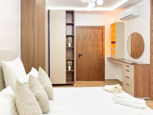 a bedroom with a white bed with a wooden door at Villa signature - Piscine prive - Spacieuse à Founty in Agadir