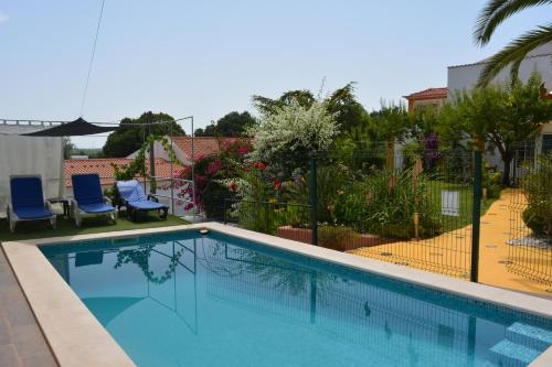 a swimming pool in a yard with two blue chairs at Villa Marquês in Vila Nova da Barquinha
