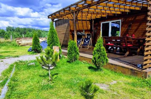 a cabin with a wooden deck and a picnic table at Domek uroczy i wilcza chatka,klimat górski na Kaszubach,balia,sauna,ognisko in Sikorzyno