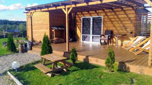 a wooden deck with a picnic table and a grill at Domek uroczy i wilcza chatka,klimat górski na Kaszubach,balia,sauna,ognisko in Sikorzyno
