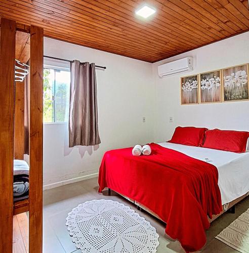 a bedroom with a bed with a red blanket at Casa de Campo Deucher in Imaruí