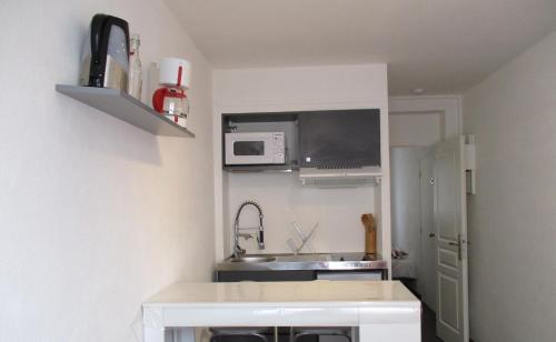 una pequeña cocina con fregadero y microondas en Studio Port Rhu Douarnenez, en Douarnenez