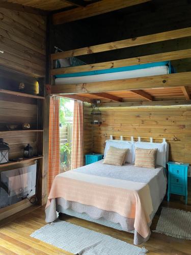 a bedroom with a bed with a wooden wall at cabanas Aconchego dos Canyons in Praia Grande