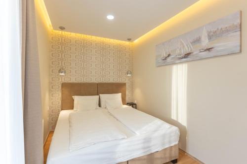 a bedroom with a bed with white sheets at Sunset Resort 113 in Fonyód