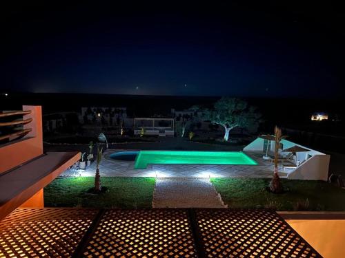 a swimming pool with lights in a backyard at night at Villa Sakina Essaouira in Ounagha