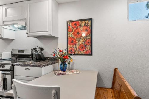 a kitchen with a table with a vase of flowers on it at Modern Downtown Oasis Sunny Garden King Beds in Longmont