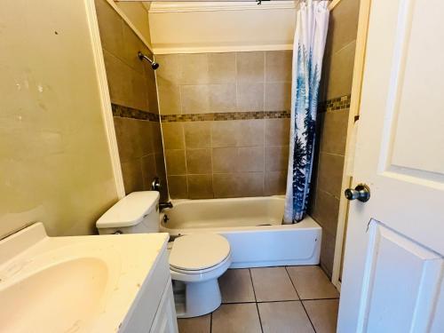 a bathroom with a toilet and a tub and a sink at Hotel O East Hemphill Burton-Flint in Burton