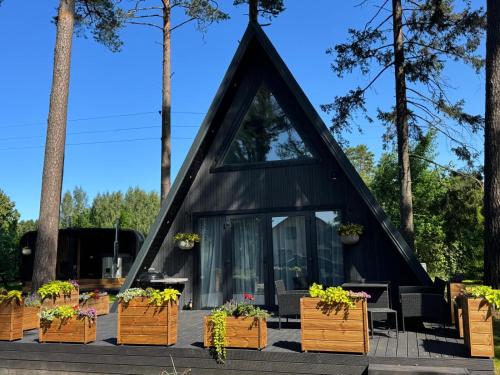 SkulteにあるPine house with sauna and hot tubの木箱に入った植物が入った黒い三角形の家