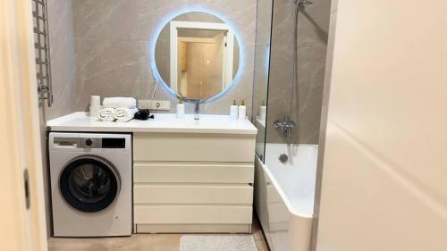 een badkamer met een wasmachine en een spiegel bij Seven Hills in Alma-Ata