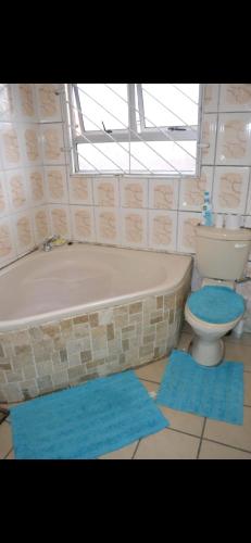 a bathroom with a tub and a toilet and blue mats at Peace Accommodation B&B in Silver Sands