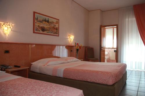 een hotelkamer met 2 bedden en een raam bij Hotel Lanterna in Porto San Giorgio
