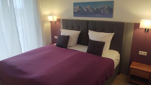 a bedroom with a bed with purple sheets and pillows at Hotel Sonnenbichl in Halblech