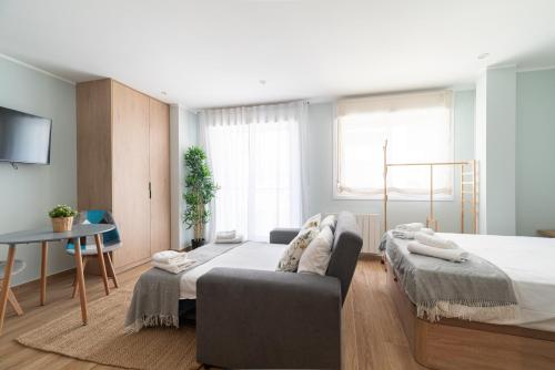 a bedroom with a bed and a couch and a table at Suites Deluxe By Roque in Vigo