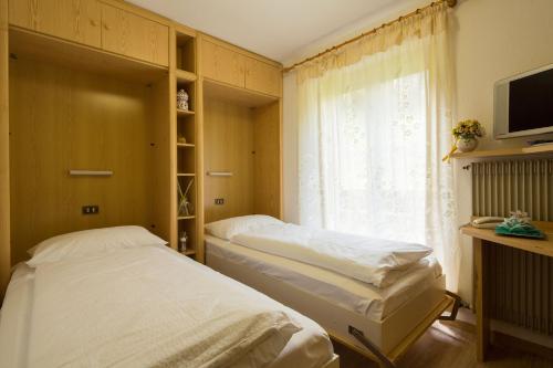 two twin beds in a room with a window at Pensione Haus Erica in Colfosco