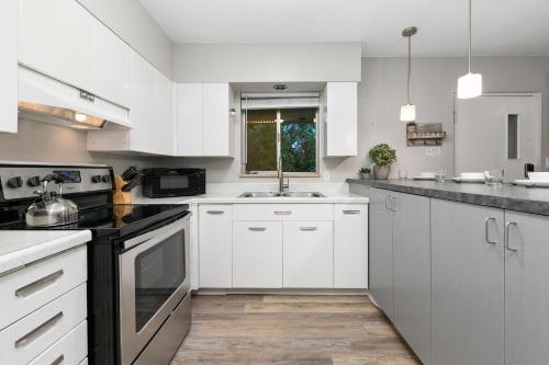 a kitchen with white cabinets and a sink at Breathtaking Condo in the Heart of Old Town in Fort Collins