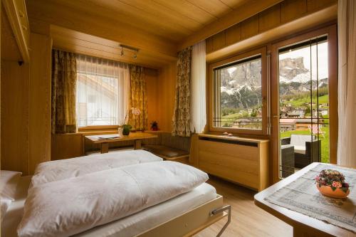 a bedroom with a bed and a large window at Pensione Erica in Colfosco