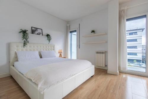 a white bedroom with a large white bed and a window at Lisbon East Residence in Lisbon