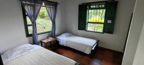 two beds in a room with two windows at Santa Lucia Estancia Rural in Guaduas