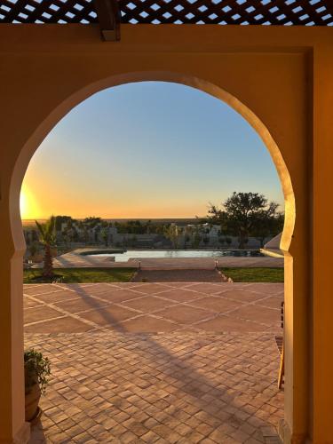 an archway in a patio with the sunset in the background at Villa Sakina Essaouira in Ounagha